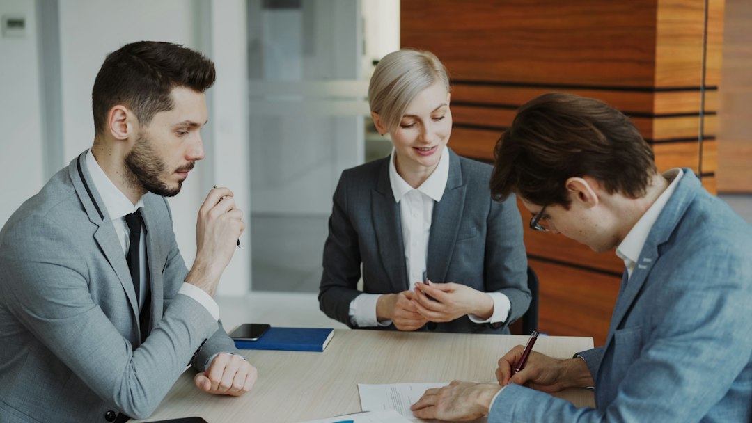 A legal/financial advisor reviewing paperwork with two clients in a modern office